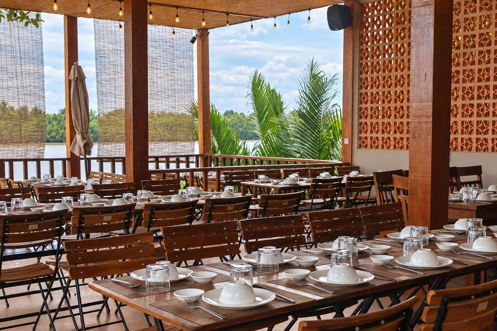 The open-air dining room set for a meal, opening onto the river