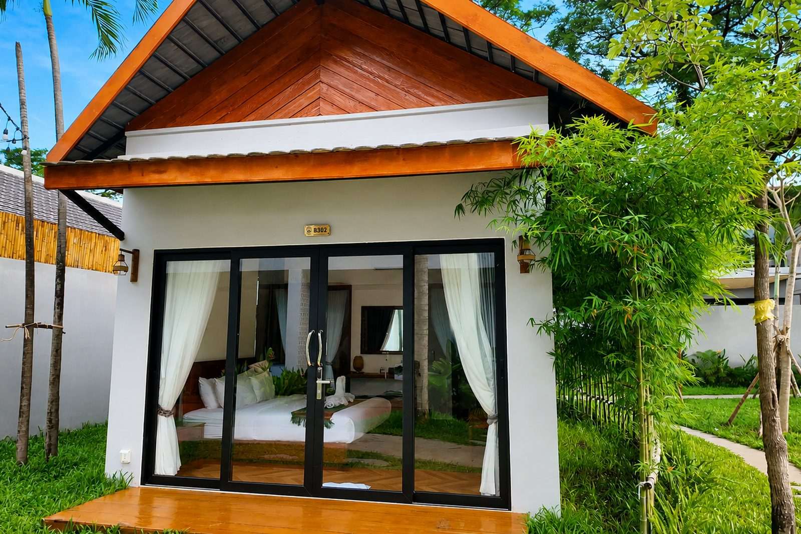 A bungalow with its glass doors opened onto the terrace, bed visible inside